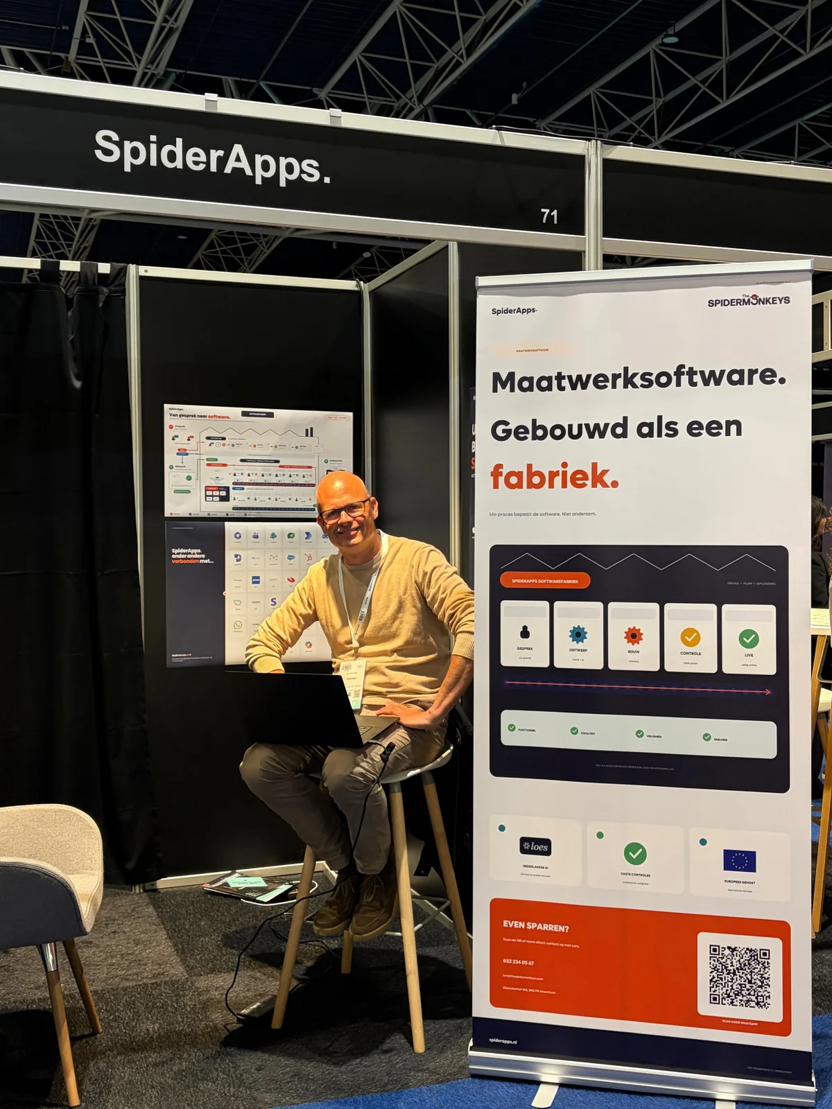 SpiderApps-stand met een laptop en de banner over maatwerksoftware bouwen als een fabriek.