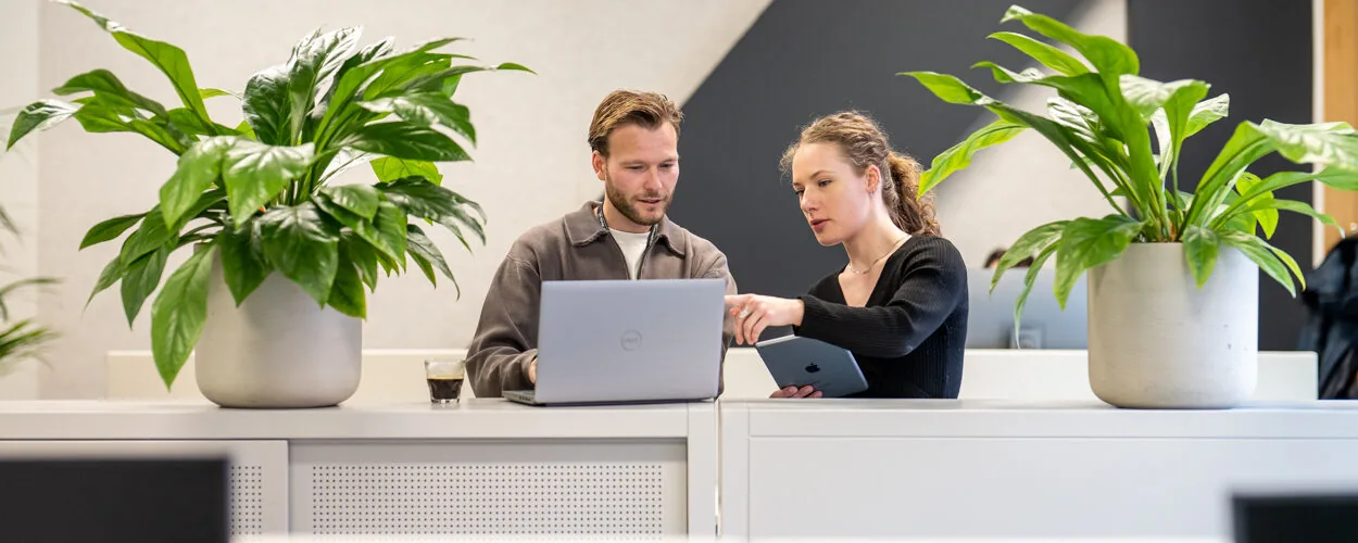 Twee collega's die samen een digitale werkomgeving bespreken.