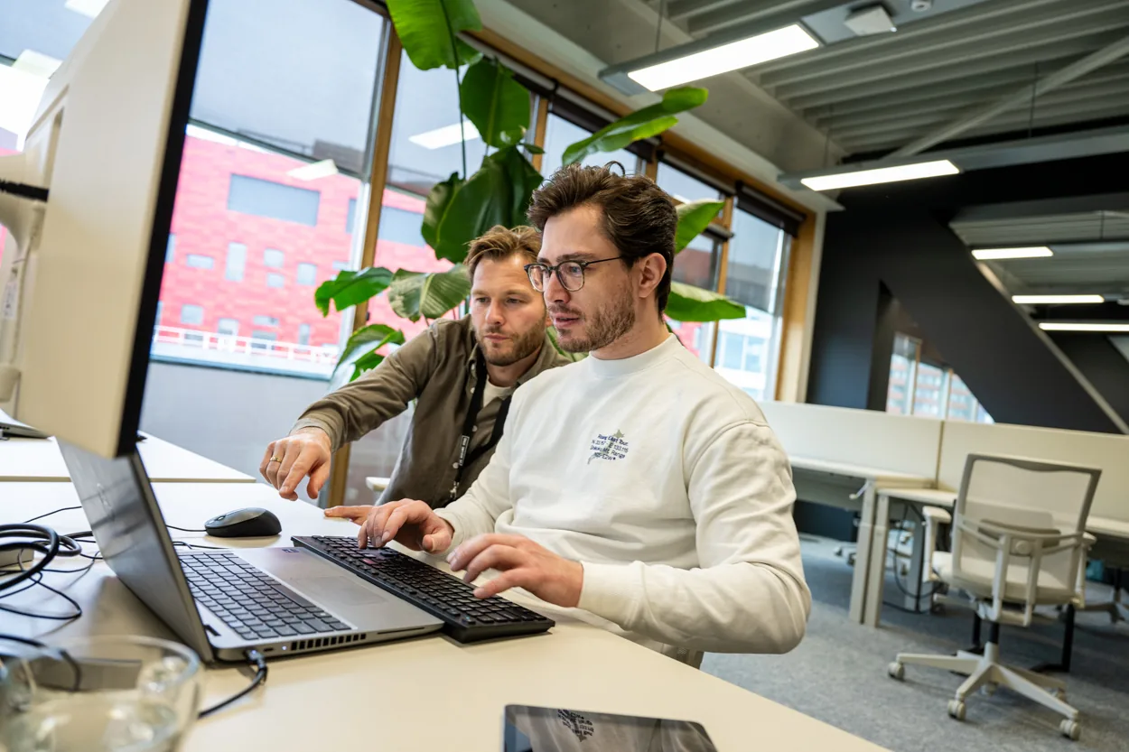 Twee collega's die samen aan een laptop werken.